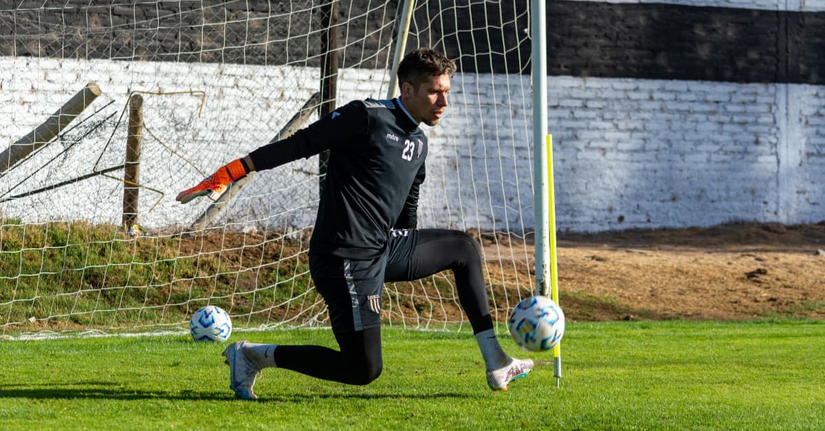 Portero de fútbol moderno despejando el balón con los pies durante un entrenamiento bajo palos.