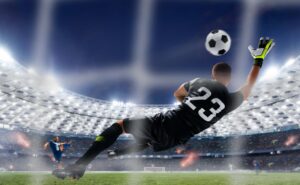 Portero con guantes profesionales realizando una estirada para detener un disparo en un estadio iluminado.