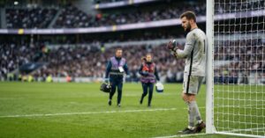 Portero de fútbol en el área observando su mano mientras el equipo médico se acerca tras una posible lesión de portero de fútbol
