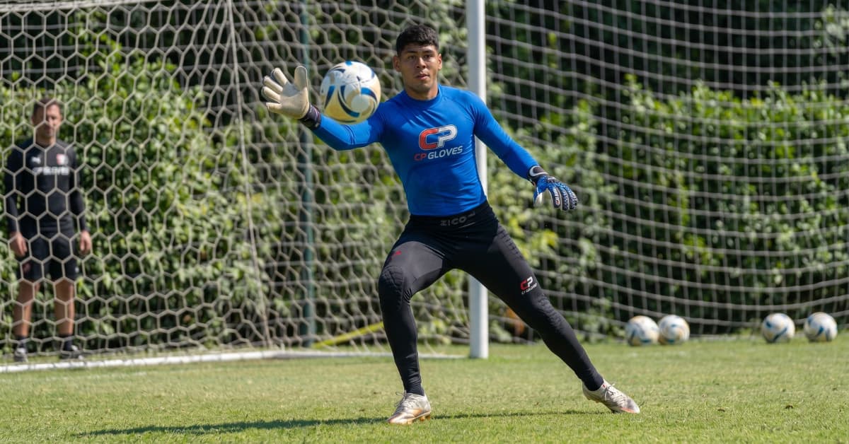 Portero de fútbol realizando un ejercicio de entrenamiento con guantes y equipamiento específico para mejorar la técnica de blocaje.